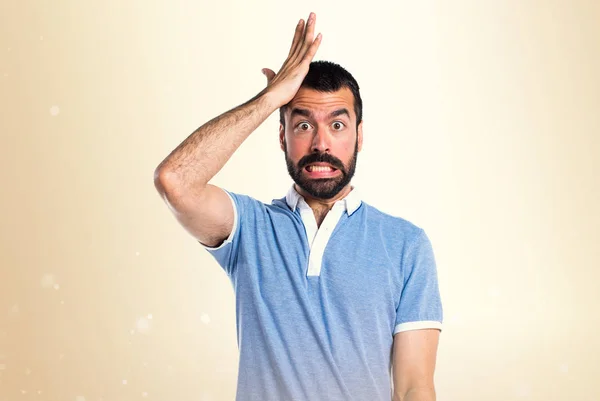 Mann mit blauem Hemd zweifelt an ockerfarbenem Hintergrund — Stockfoto