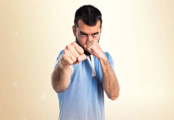 Man met blauwe shirt geven een punch op okergeel achtergrond — Stockfoto