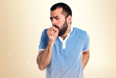 Adam mavi gömlek çok koyu sarı zemin üzerine öksürük ile