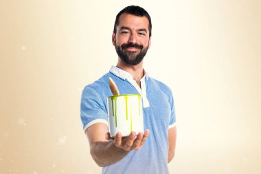 Mavi gömlekli bir boya pot koyu sarı arka plan üzerinde tutan adamla