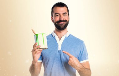 Mavi gömlekli bir boya pot koyu sarı arka plan üzerinde tutan adamla