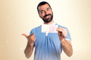 Mavi gömlek koyu sarı arka plan üzerinde bir sürü para alarak adamla