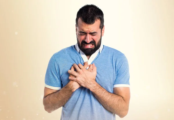 Hombre con camisa azul con dolor de corazón sobre fondo ocre —  Fotos de Stock