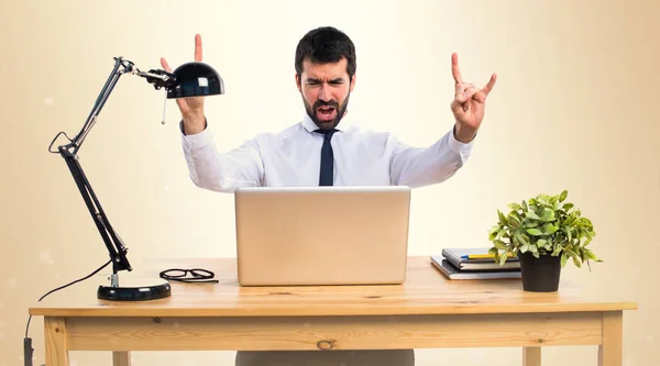 Empresario en su oficina haciendo gesto de cuerno en ocre backgroun —  Fotos de Stock