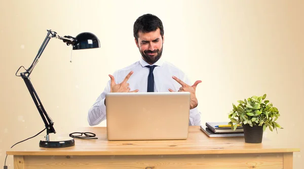 Uomo d'affari nel suo ufficio che fa gesti di corno su backgroun ocra — Foto Stock