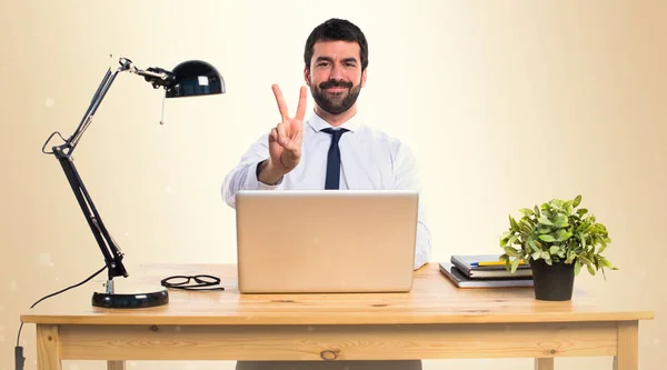 Empresario en su oficina contando dos sobre fondo ocre — Foto de Stock