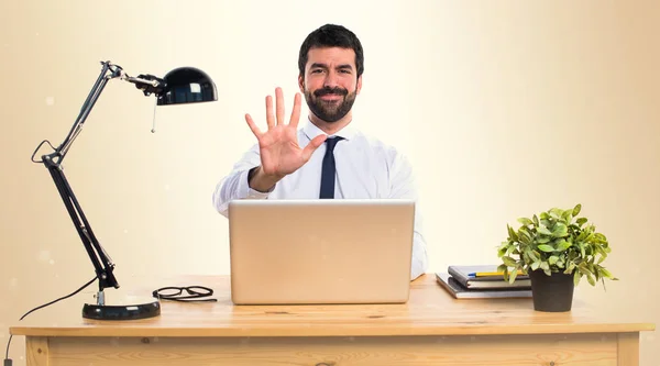 Affärsman i hans kontor räknar fem på ockra bakgrund — Stockfoto