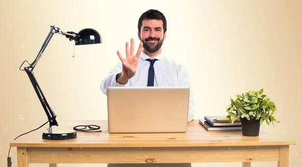 Homme d'affaires dans son bureau comptant quatre sur fond ocre — Photo