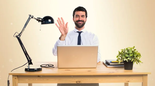 Homme d'affaires dans son bureau saluant sur fond ocre — Photo