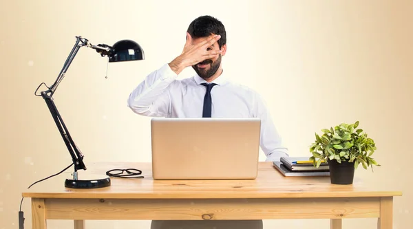 Zakenman in zijn kantoor die betrekking hebben op zijn gezicht op okergeel achtergrond — Stockfoto