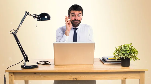 Businessman in his office with his fingers crossing on ocher bac — Stock Photo, Image