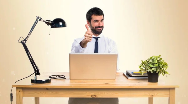 Affärsman i hans kontor med tumme upp på ockra bakgrund — Stockfoto