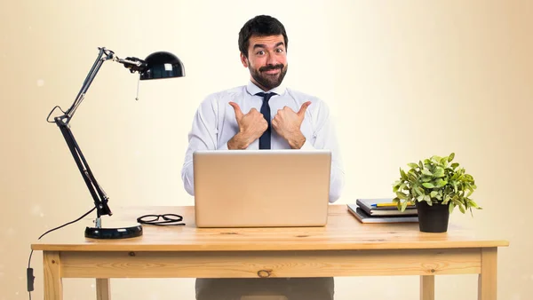 Zakenman in zijn kantoor met duim omhoog op okergeel achtergrond — Stockfoto