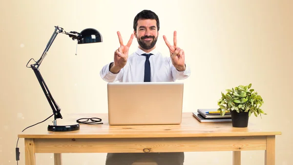 Бизнесмен в своем офисе делает победный жест на ocher backgro — стоковое фото