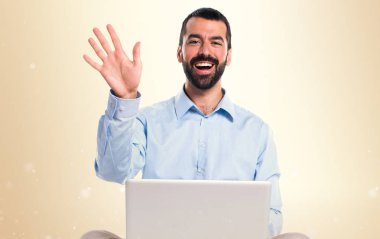 Adam koyu sarı zemin üzerine selamlayan dizüstü bilgisayar ile