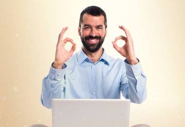 Adam koyu sarı arka plan üzerinde oturum Tamam yapma dizüstü bilgisayar ile