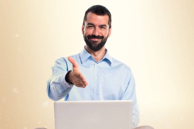 Dizüstü bilgisayar bir anlaşma üzerinde koyu sarı arka plan ile adam