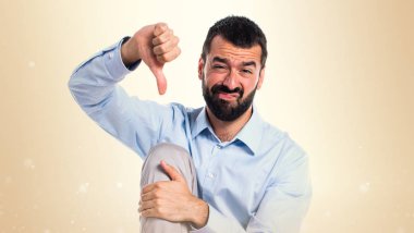 Koyu sarı zemin üzerine kötü sinyal yapan yakışıklı erkek