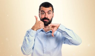 Yakışıklı adam iyi-kötü işareti üzerinde koyu sarı arka plan yapma