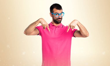 Aşağıyı gösteren koyu sarı arka plan üzerinde renkli giysileri ile adam