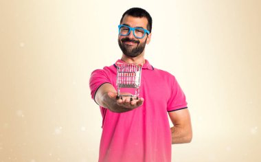 Adam oche üzerinde tutmak bir süpermarket arabası oyuncak renkli giysileri ile