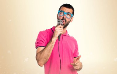 Adam renkli giysileri okra backg üzerinde mikrofon ile şarkı ile