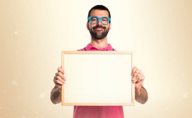 Adam boş bir afişini okra arkasında tutarak renkli giysileri ile