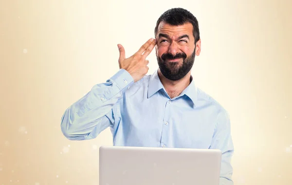 Homem com laptop fazendo gesto de suicídio em fundo ocre — Fotografia de Stock