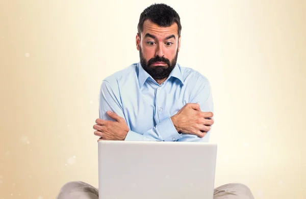 Man met laptop bevriezen op okergeel achtergrond — Stockfoto