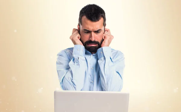 Man met laptop die betrekking hebben op zijn oren op okergeel achtergrond — Stockfoto