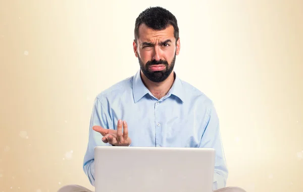 Moe man met laptop op okergeel achtergrond — Stockfoto