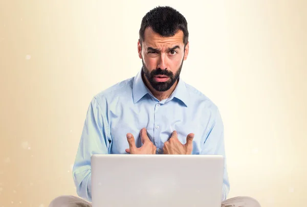 Man met laptop doen verrassing gebaar op okergeel achtergrond — Stockfoto