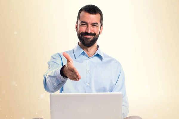 Homem com laptop fazendo um acordo em outro fundo — Fotografia de Stock