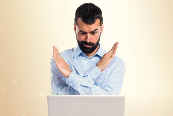 Homem com laptop fazendo nenhum gesto no fundo ocre — Fotografia de Stock