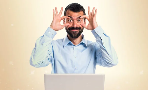 Άνθρωπος με φορητό υπολογιστή που δείχνει κάτι σε φόντο ώχρα — Φωτογραφία Αρχείου