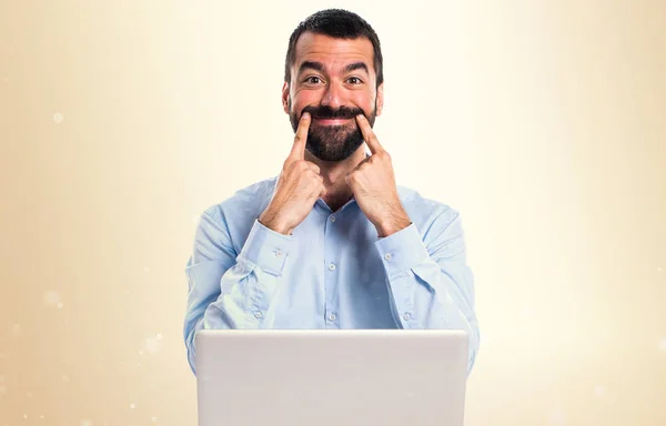 Homem feliz com laptop em fundo ocre — Fotografia de Stock