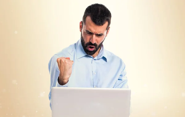 Lucky man with laptop on ocher background