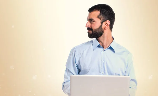 Mannen med laptop ser laterala på ockra bakgrund — Stockfoto