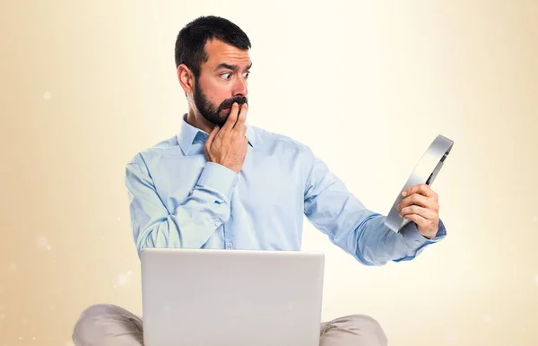 Man met laptop houdt een horloge op okergeel achtergrond — Stockfoto