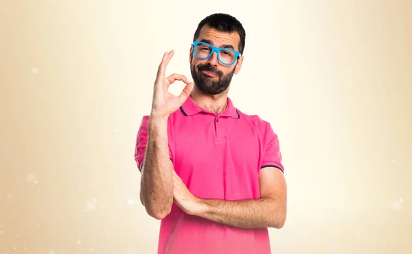 Homme avec des vêtements colorés faisant signe OK sur fond ocre — Photo