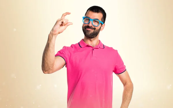 Άνθρωπος με πολύχρωμα ρούχα κρατώντας κάτι στο φόντο ώχρα — Φωτογραφία Αρχείου