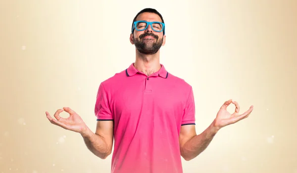 Man met kleurrijke kleding in zen positie op okergeel achtergrond — Stockfoto