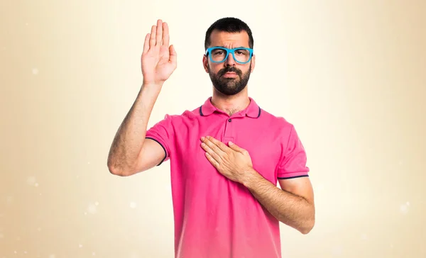 Man with colorful clothes doing an oath on ocher background — Stock Photo, Image