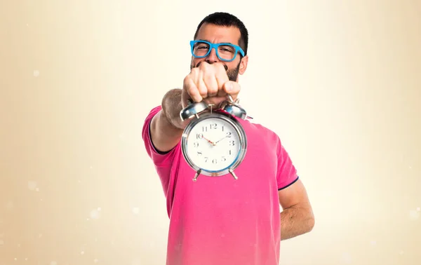 Mannen med färgglada kläder håller vintage klocka på ockra backgro — Stockfoto