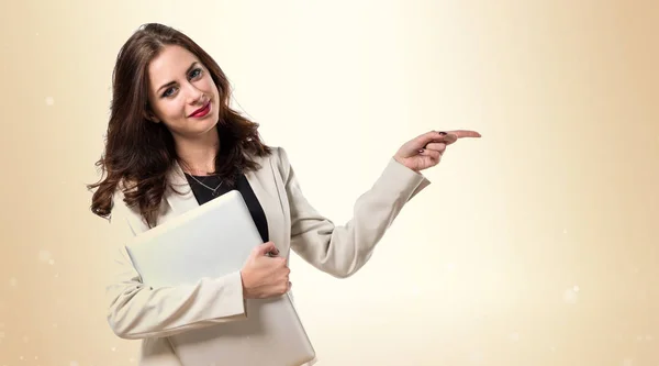 Mujer de negocios bastante joven con el ordenador portátil y apuntando a la lat — Foto de Stock