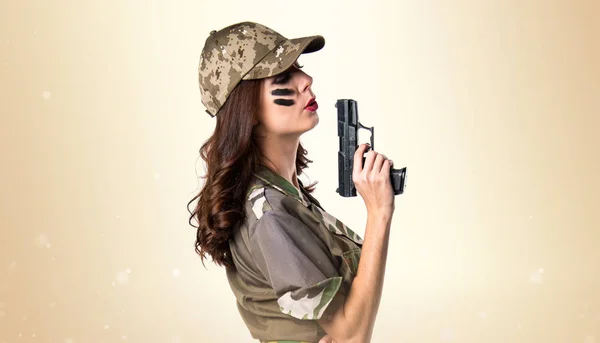 Askeri kız bir tabanca koyu sarı arka plan üzerinde tutan — Stok fotoğraf