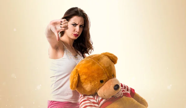 Pretty brunette girl with pajamas making bad signal on ocher bac — Stock Photo, Image