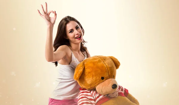 Girl with pajamas making OK sign and playing with stuffed animal — Stock Photo, Image