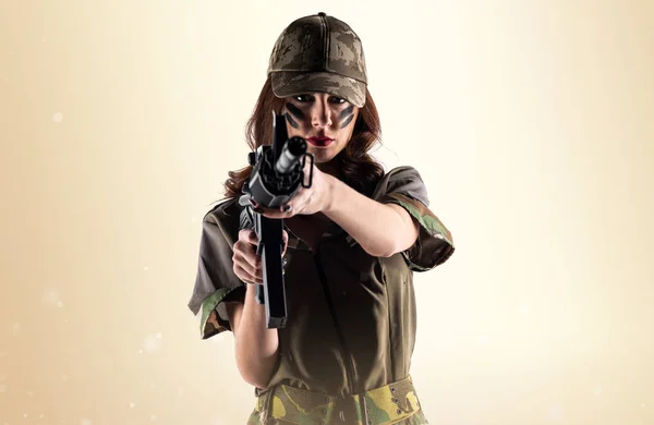 Military woman holding a rifle on ocher background — Stock Photo, Image