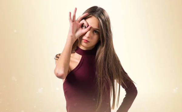 Junges Teenager-Mädchen zeigt etwas auf ockerfarbenem Hintergrund — Stockfoto